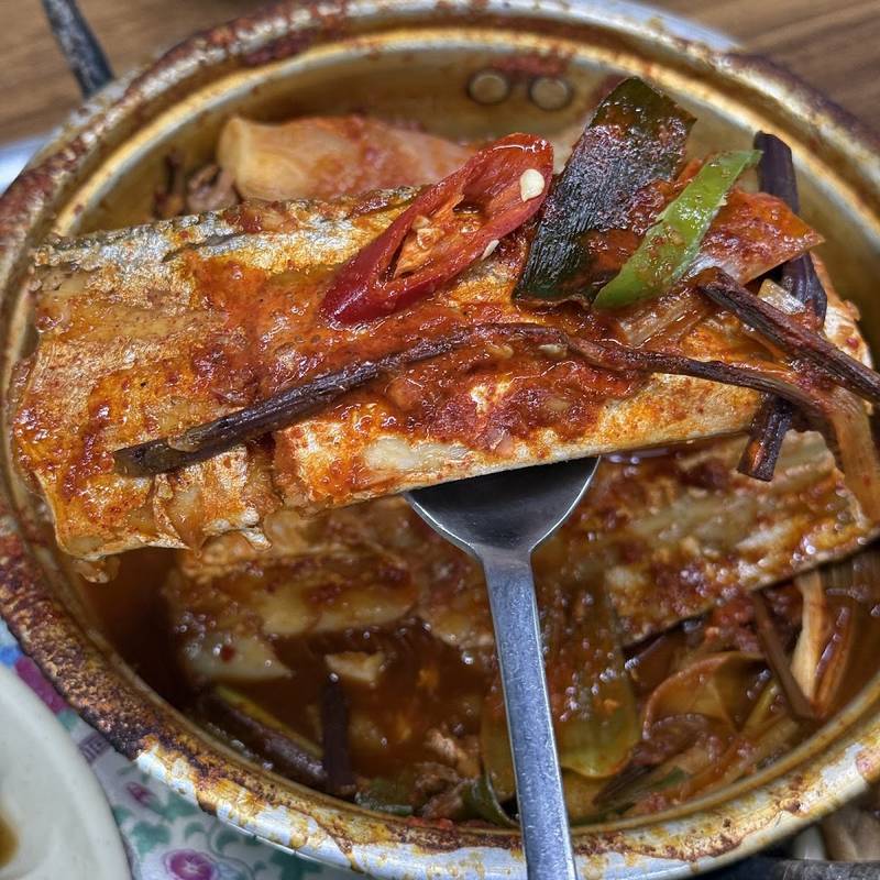 냄비째 끓여 나온 매콤한 갈치조림을 숟가락으로 뜨는 모습
